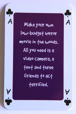 Playing card Ace of clubs reads: Make your own low budget horror movie in the woods. All you need is a video camera, a tent and three friends to act terrified.