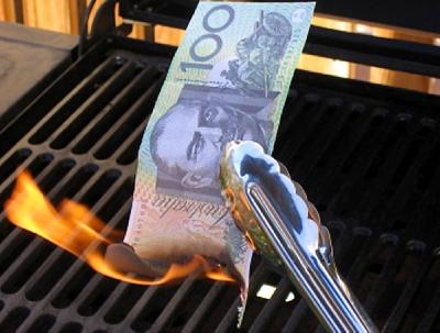 Photo of a one hundred dollar note being held with tongs. It is on fire.