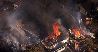 A photo of a house and car burning in a fire storm