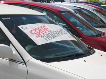 A photo of a car for sale with a sign over the windscreen that reads save thousands