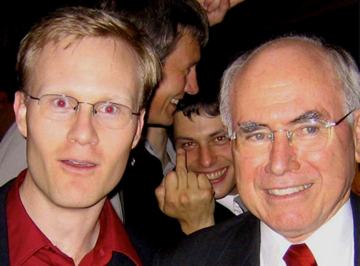 This photo was taken a few years ago. I am on the left and former Prime Minister John Howard is on the right. In the background in between us is the cheeky colleague. He has a big grin, is looking straight to the camera and is sticking his middle finger up