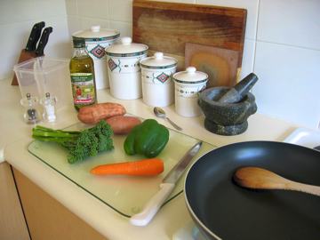 A photo of a kitchen bench with various vegetables on a cutting board