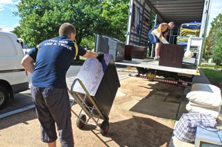 A photo of a removalist moving a item of furniture on to a removal truck