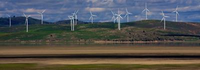 A photo of many wind turbines over looking a lake