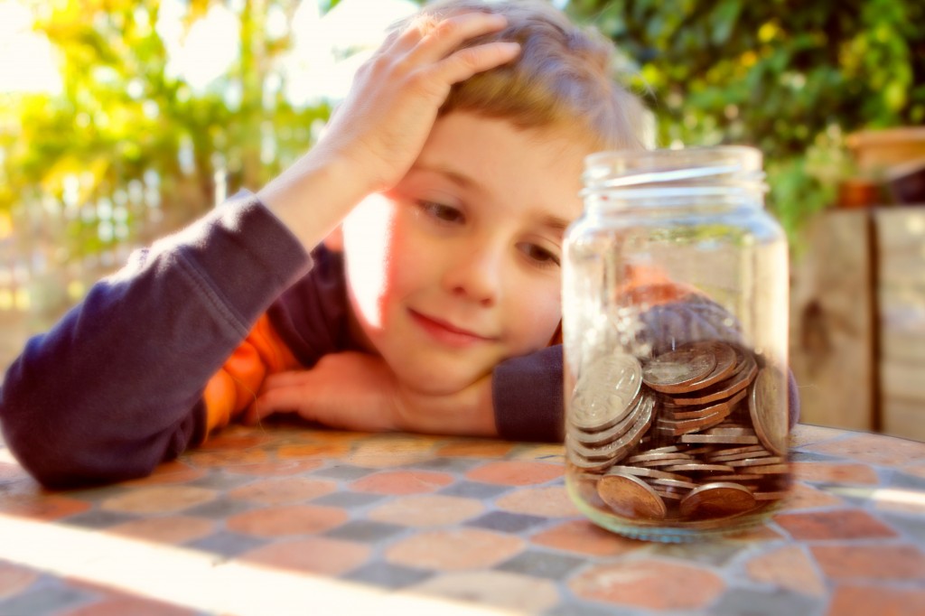 Photo of a piggy bank with a young boy in the background.