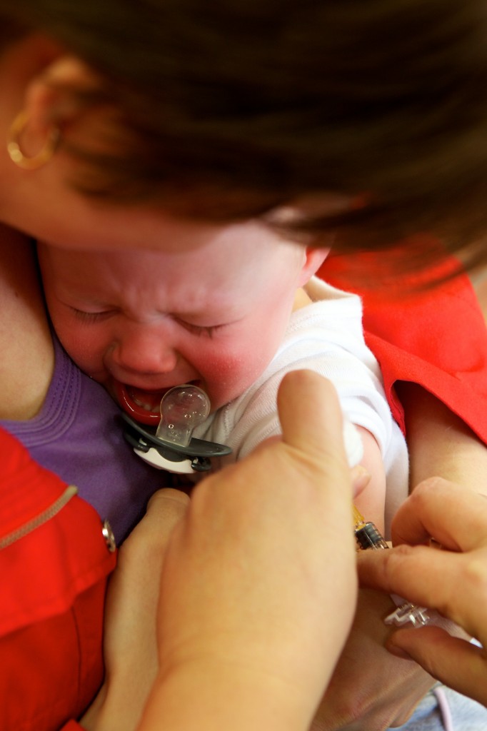 Photo of a toddler being immunised. It is not happy.