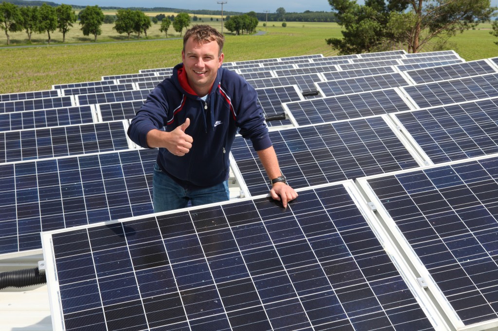 Photo of a man surrounded by pv solar giving the camera the thumbs up.